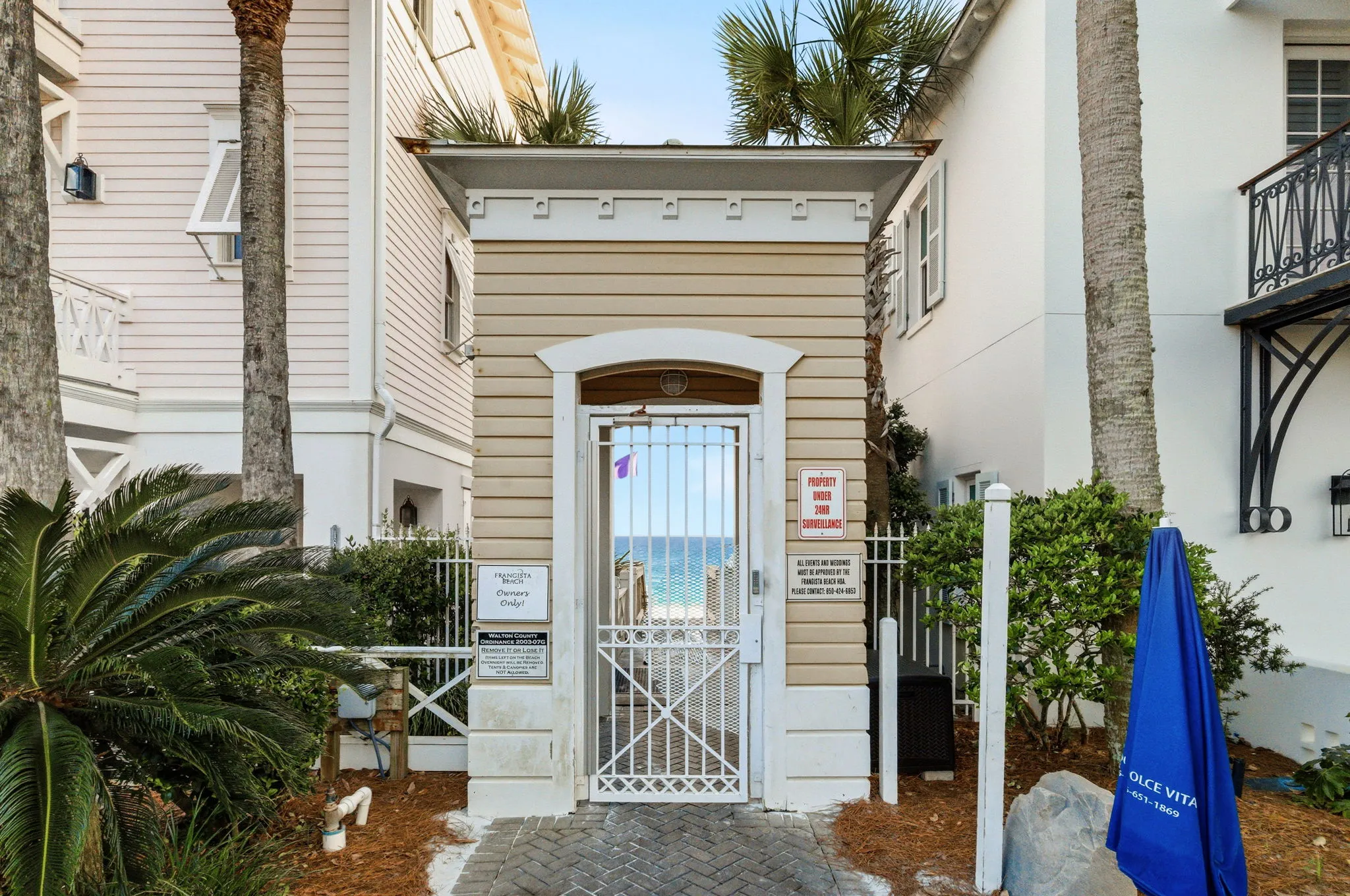 Deeded beach access boardwalk gate with a glimpse of emerald water beyond