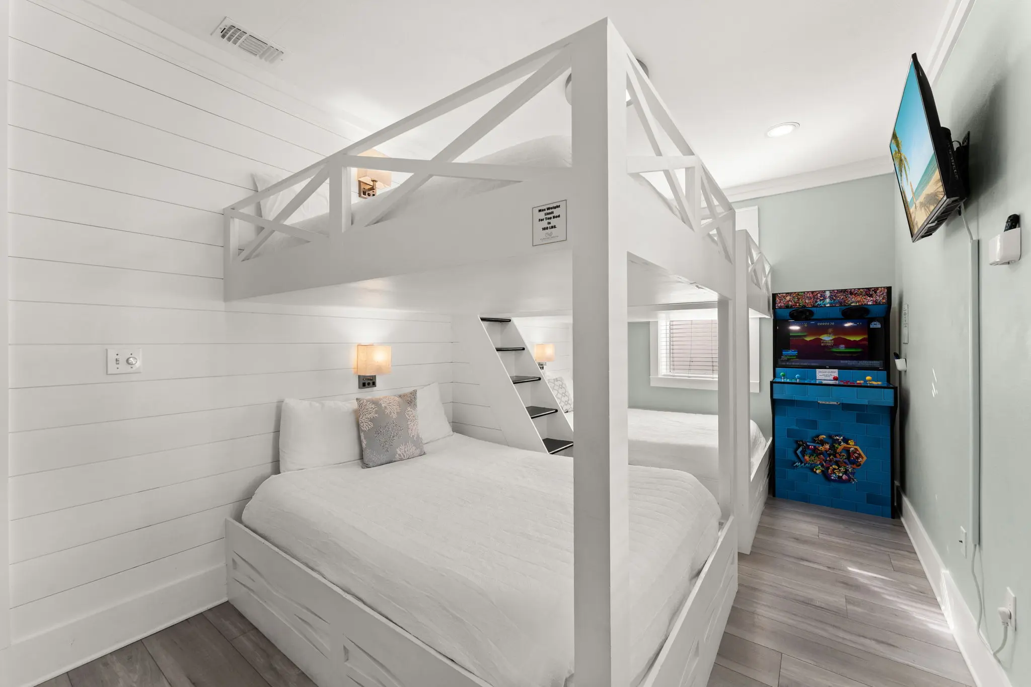 Custom queen-over-queen bunks with shiplap and arcade machine