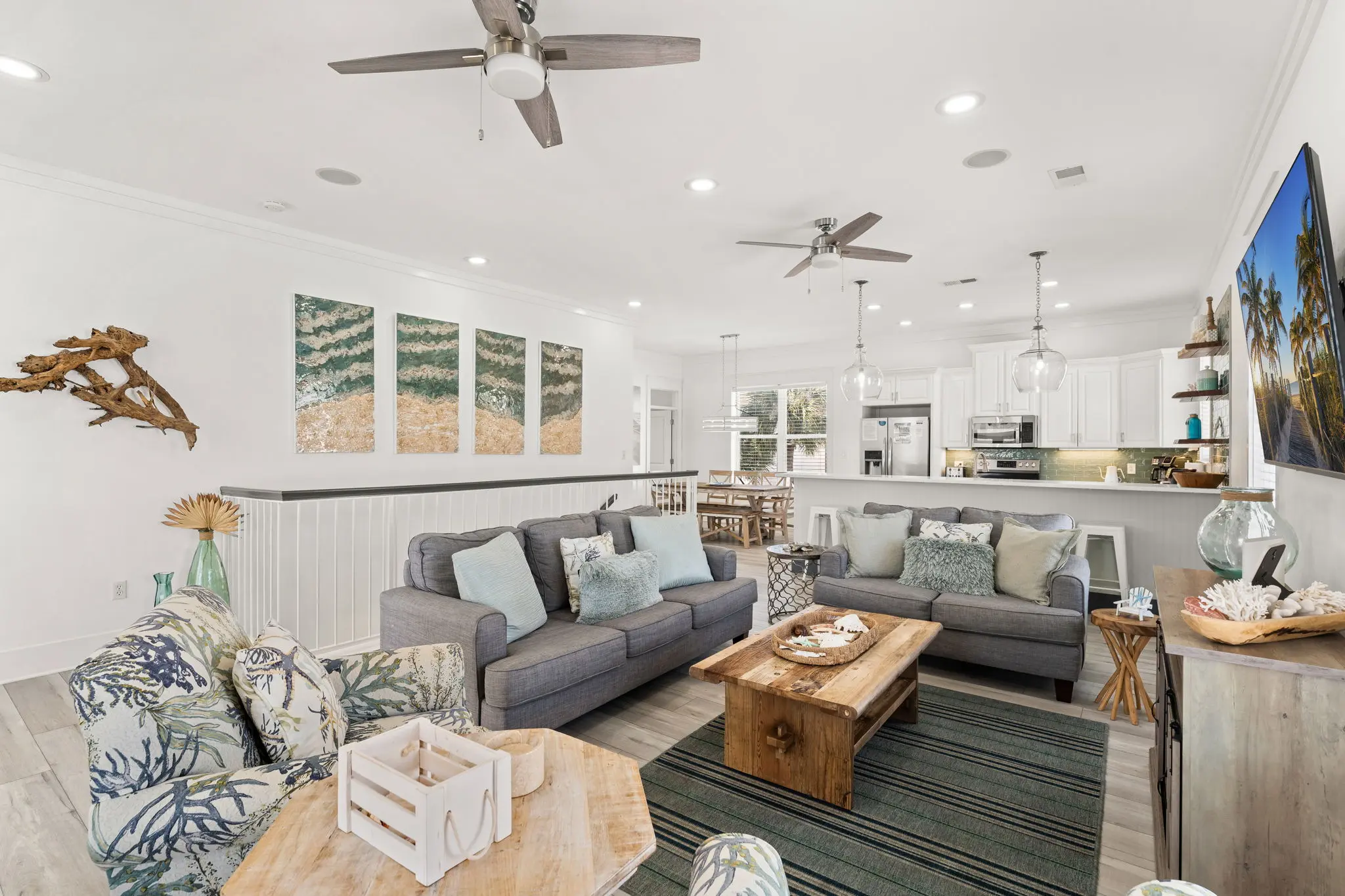 Open-concept living area with gray sectionals and coastal art
