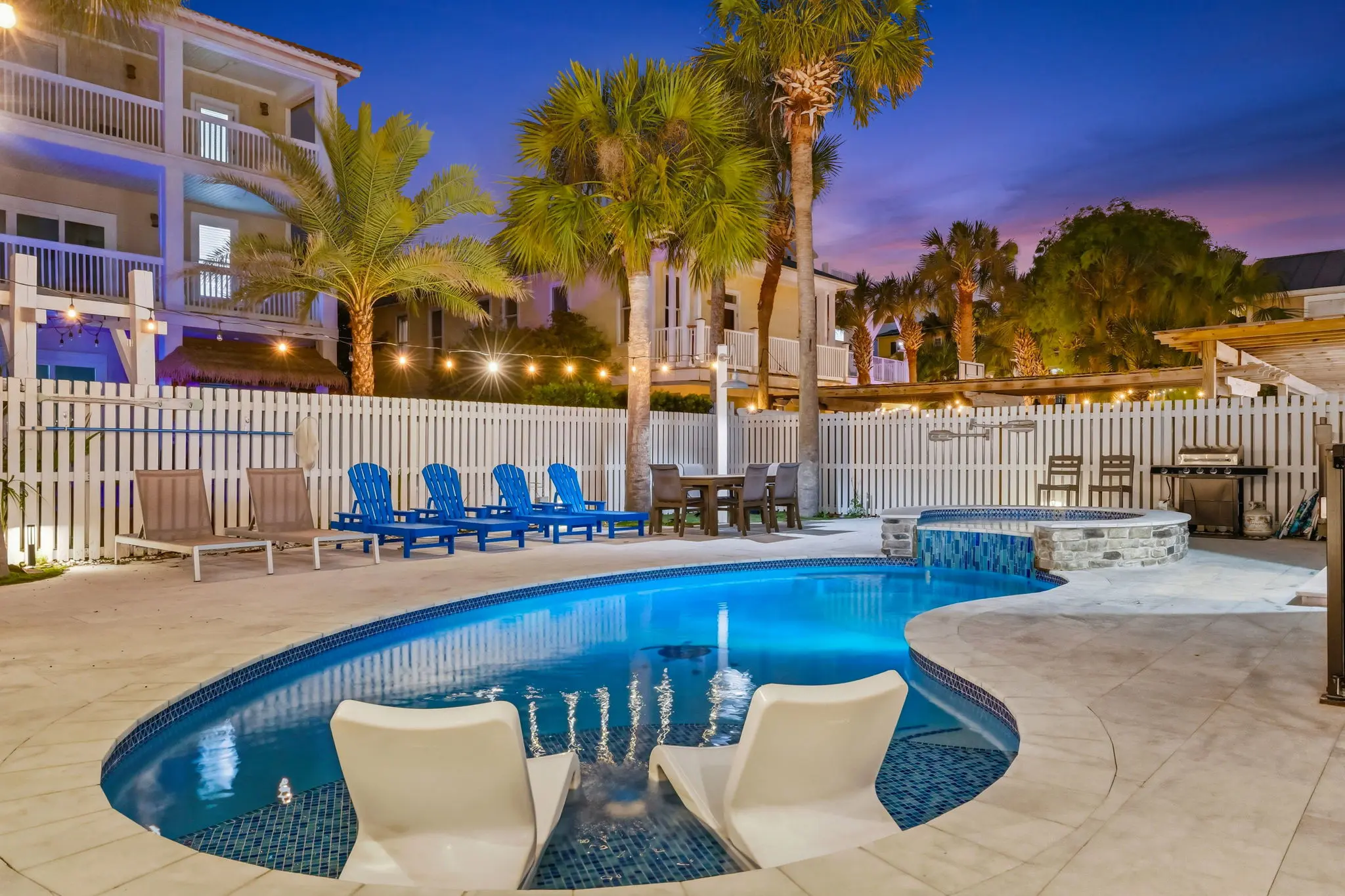 Pool at twilight with in-pool lounge chairs and spa waterfall